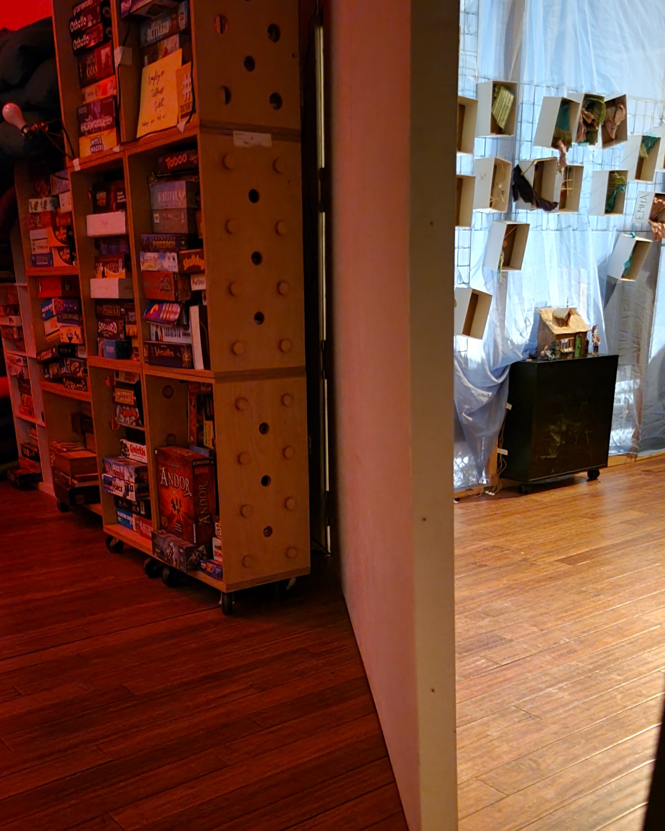 A hallway with bookshelves divided by a wide door, cracked open to reveal another room.