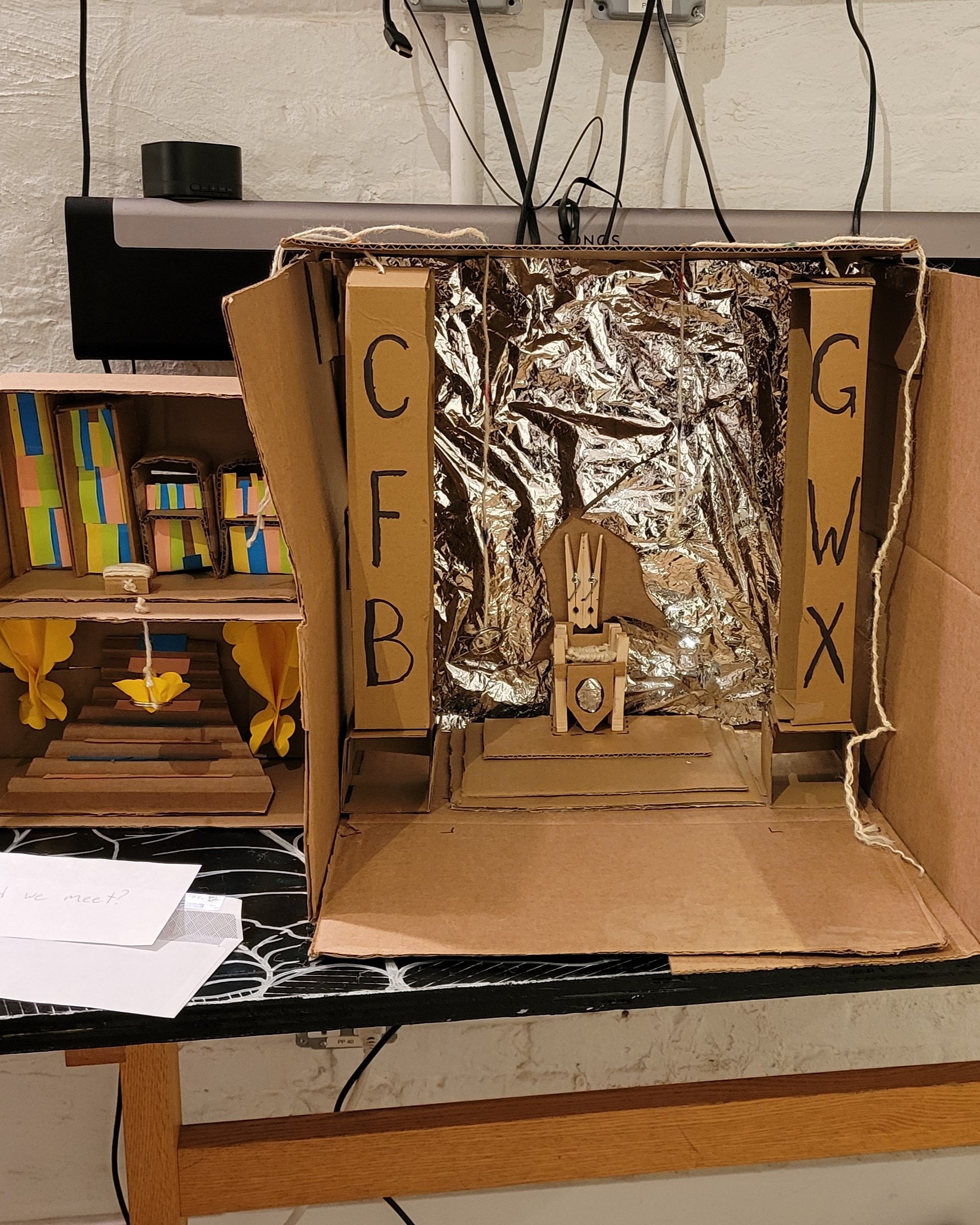 Cardboard dollhouse of a palace with a large throne room and a throne made of clothespins.