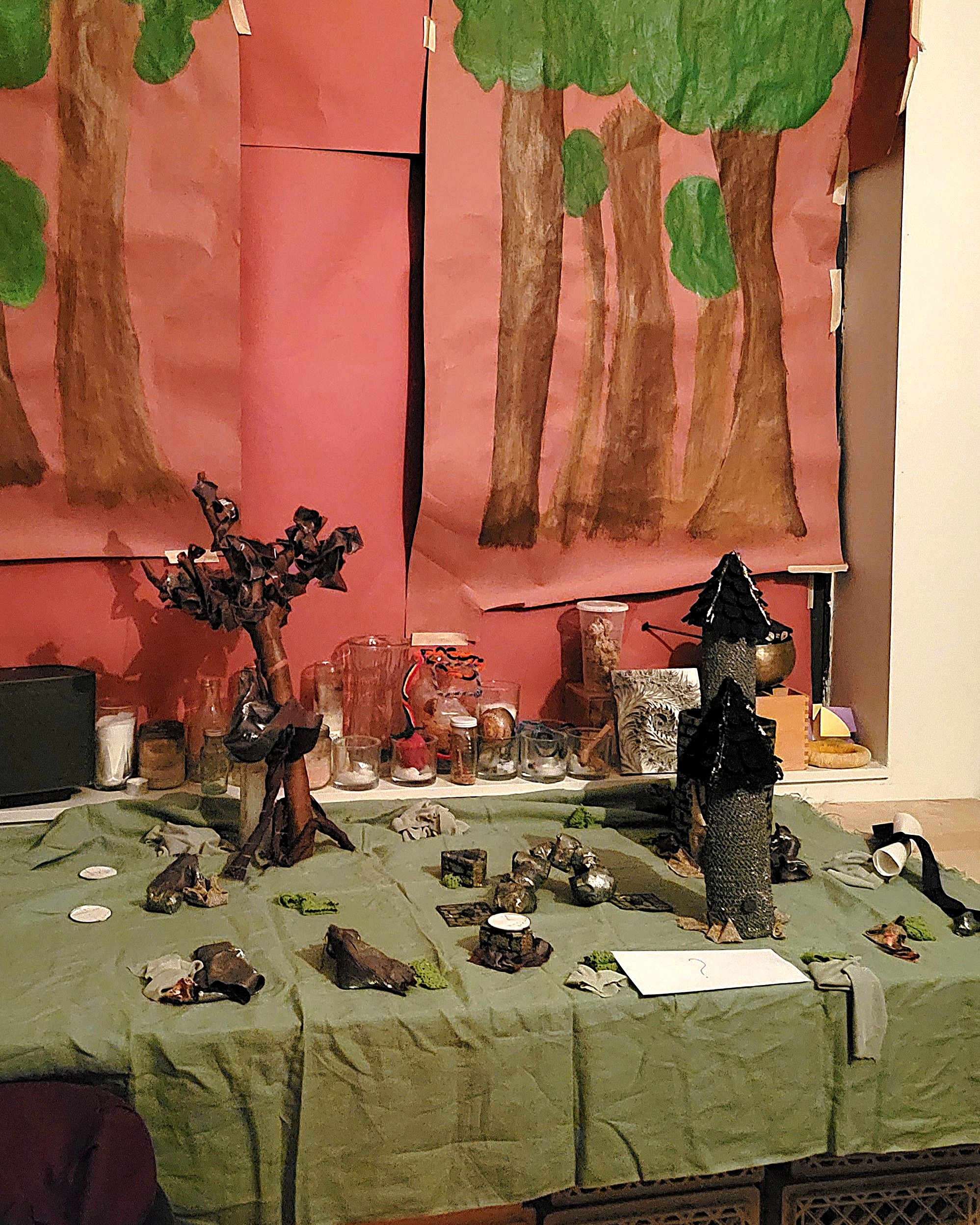 Diorama of two wizard towers and a rock arch on a fabric forest floor.